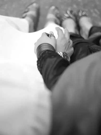 An artistic, black and white detail shot focusing on the couple holding hands, symbolizing their connection and journey together.