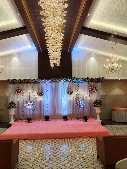 Here you can see the same pink stage setup from a distance, showing how it fits within the larger banquet hall. The grand chandeliers of the venue complement the stage lighting perfectly.