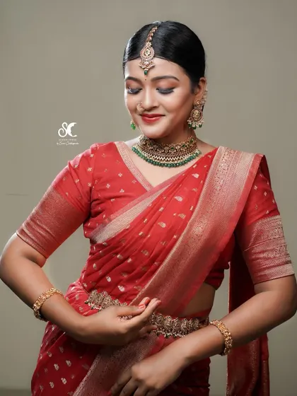 A Sabyasachi-inspired semi-bridal look. The classic red saree and traditional jewelry are captured with a soft, warm light to create a timeless and elegant portrait.