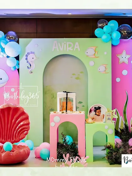 The main cake-cutting area for Avira's underwater party, featuring a large red clamshell prop and a custom-designed backdrop.