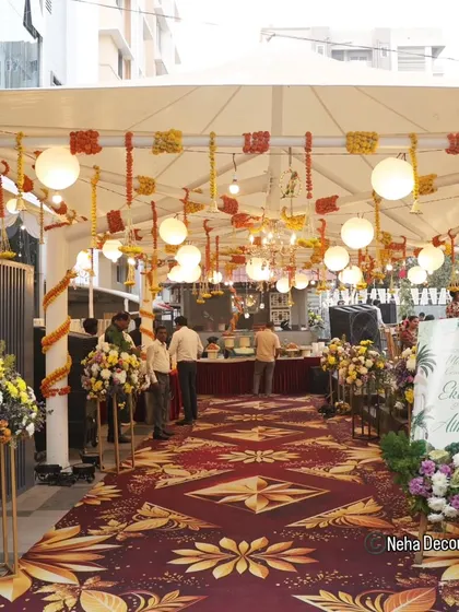A grand entrance for a daytime Mehendi ceremony. We used a beautiful patterned carpet runner, floral arrangements on pedestals, and a ceiling decorated with hanging lanterns and marigold strings.