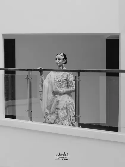 A wide, minimalist black and white shot of the bride on a balcony, creating a sense of quiet contemplation before the ceremony.