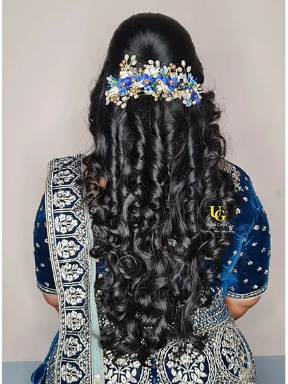A romantic and modern hairstyle for a reception. We created soft, cascading curls and accessorized them with a beautiful blue floral clip to match the client's lehenga.
