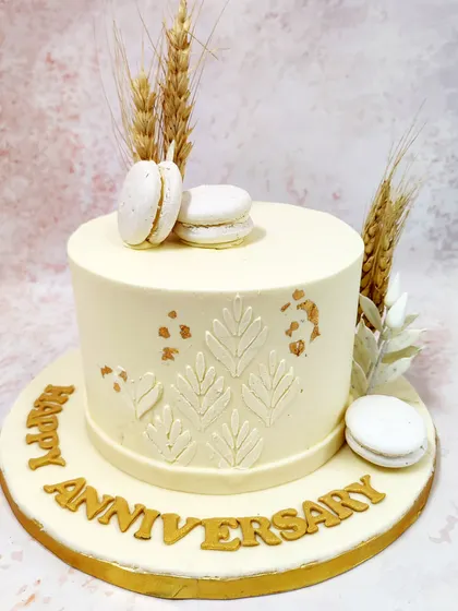 We embrace rustic charm with this elegant anniversary cake. A simple white cake is decorated with an embossed leaf pattern, gold leaf, and sprigs of wheat, creating a minimalist and natural design that is both modern and timeless.