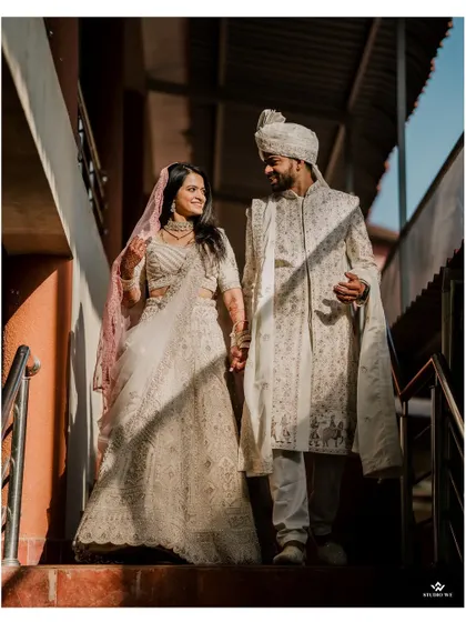 The couple walks down the stairs, sharing a look of love. This shot captures a quiet, candid moment during their wedding day.