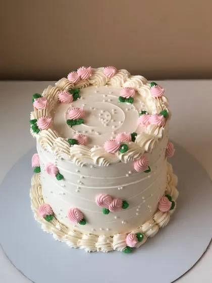 A classic vintage-style cake with delicate pink rosebuds and white piping.