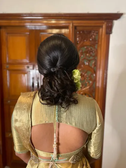 A simple and chic messy bun, adorned with a single fresh flower. This is an elegant and modern hairstyle perfect for a reception or pre-wedding event.