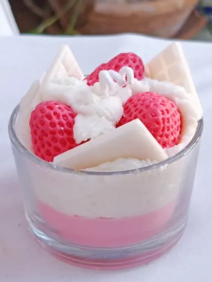 The strawberry ice cream candle, presented on a white surface to emphasize its colors.