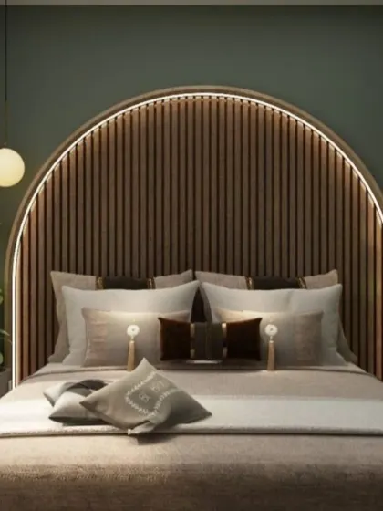 An arched, fluted wood headboard with backlighting creates a warm and inviting focal point in this bedroom. The deep green wall color and potted plants add a touch of nature-inspired tranquility.