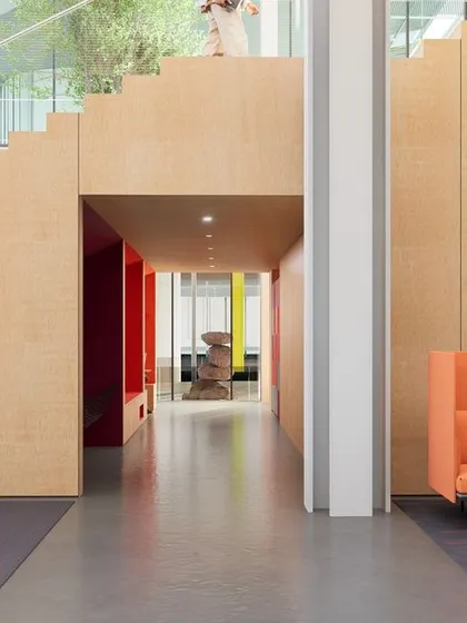 A view from under the social staircase at the 'ePositive' campus, revealing colorful breakout spaces beyond. The design uses warm wood and pops of bright color to create a playful yet sophisticated atmosphere that encourages creativity and interaction.