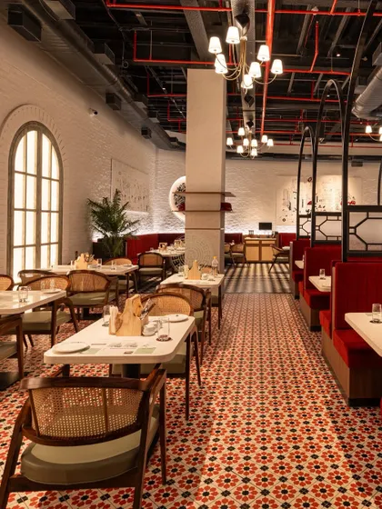 We used two different flooring patterns to define the space. The vibrant red and black mosaic tiles in this section complement the cane-back chairs and arched windows.