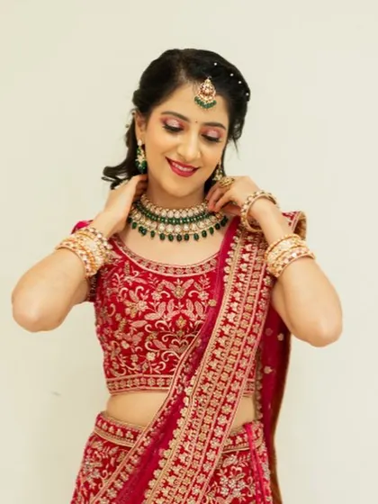 The bride adjusting her necklace, showcasing her radiant skin and the beautiful details of her reception makeup.