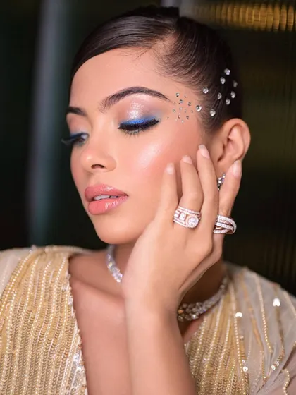 Blue vibes for a cocktail look. This pop of color on the eye, combined with face gems, creates a fun, glamorous, and modern party look.
