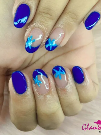 A beautiful and artistic design with a solid blue base and accent nails featuring hand-painted blue and light blue flowers.
