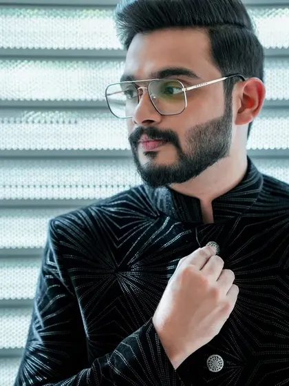 A close-up of the groom's engagement look. The black velvet jacket with a geometric pattern is a unique and stylish choice.