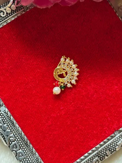 A delicate nath design with a peacock motif, studded with small stones and pearls.