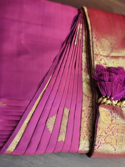 A beautiful magenta silk saree, box-folded with the decorative tassels displayed. It’s not just about convenience; it’s also about presenting the saree beautifully.