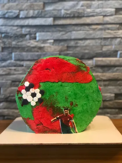 Another angle of the Ronaldo football theme cake, showing the texture of the buttercream "pitch" and the arrangement of the edible decorations. This was a red velvet cake with vanilla whipped cream.