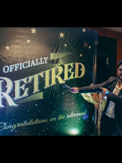 Officially retired. Pointing to the backdrop at a retirement party, celebrating the start of a new chapter for the guest of honor.