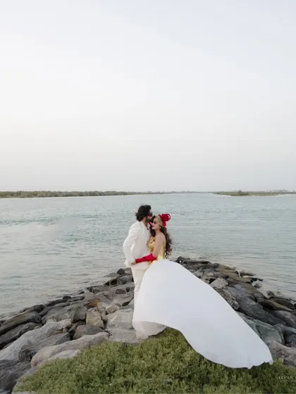 A dramatic portrait on the shores of Abu Dhabi. The flowing white dress against the rocks and water creates a powerful, high-fashion image.