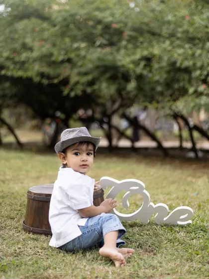 A candid shot of this little boy looking back, wearing a stylish hat for his outdoor first birthday shoot.
