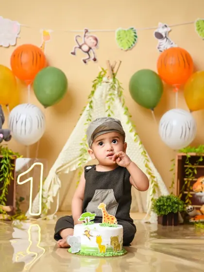Welcome to the jungle! A one-year-old ready for his cake smash in our adventurous jungle-themed setup.