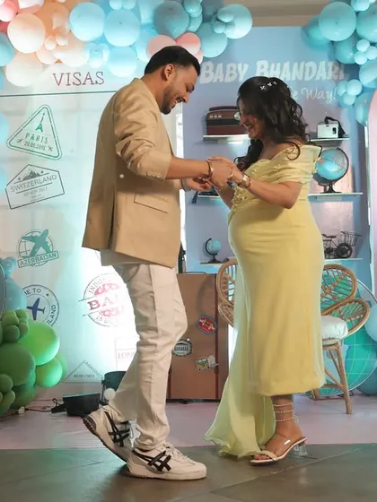 A sweet, candid moment of the couple dancing in front of their travel-themed backdrop.