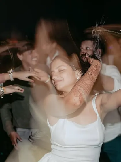 A motion-blur shot of the bride dancing with her arms raised, lost in the music and the moment.