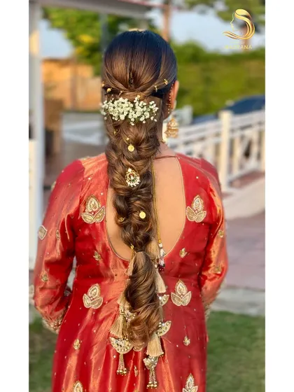 A beautiful messy braid adorned with baby's breath and traditional parandi tassels, perfect for a Punjabi bride or a Mehendi function.
