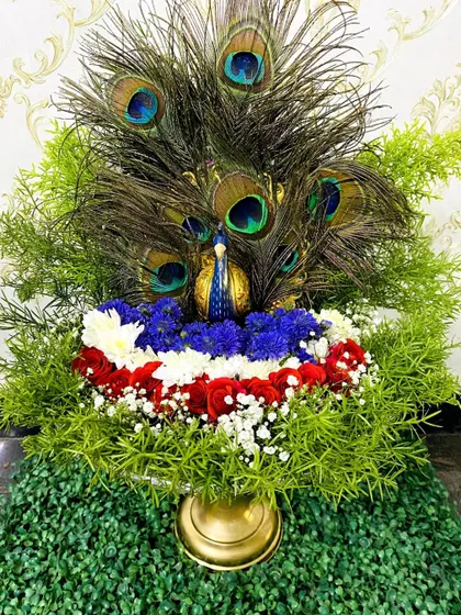 I design unique, thematic trays like this stunning peacock arrangement. A golden peacock figurine is surrounded by peacock feathers, lush greenery, and colorful flowers, creating a vibrant and auspicious centerpiece for any celebration.