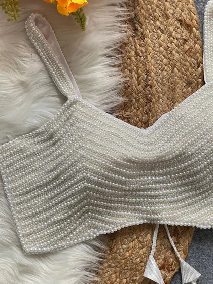 A close-up of the white pearl blouse, showing the texture and craftsmanship.