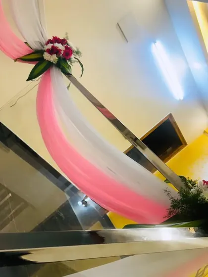 A simple railing decoration using pink and white drapes with a small floral accent.