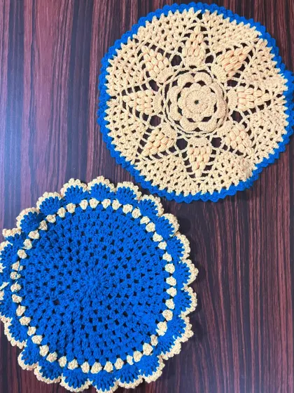 Two contrasting thalkosh designs, one in blue with a cream border and the other in cream with a blue border.