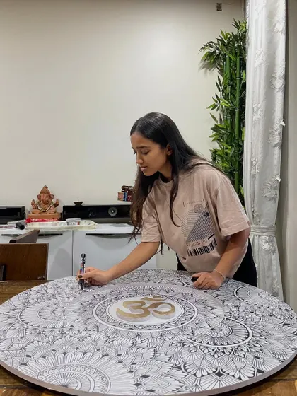 Adding the final touches to a custom mandala featuring a golden Om symbol at its center. Each piece is approached with intention and care.