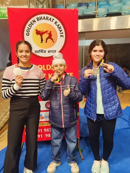 Three of our young students, two girls and a boy, proudly displaying their medals.