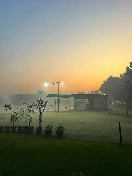 A misty morning view of the putting green and practice bays, creating a serene and beautiful atmosphere.