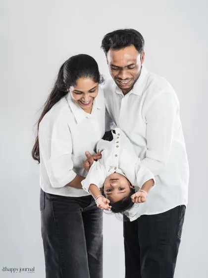 A fun and playful family moment captured in the studio. The parents swing their child, creating a feeling of movement and pure, infectious laughter.
