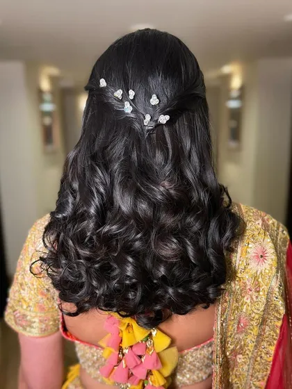 A simple half-updo with a twist, adorned with small, sparkling butterfly clips. This is a sweet and romantic style for a daytime event.