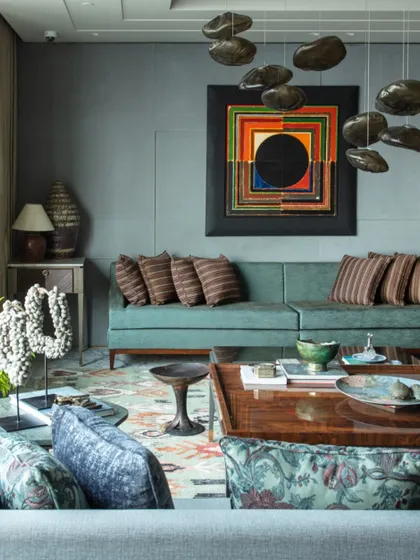 The living room features a stunning artwork by S.H. Raza, which takes center stage. The space is furnished with custom pieces from Furgonomics, collectibles from Chor Bazaar, and a luxurious carpet from Jaipur Rugs.