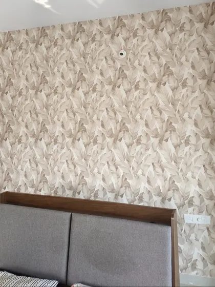 A subtle leaf pattern in neutral tones provides a textured and sophisticated backdrop for this bedroom. It complements the grey headboard and creates a calm, cohesive look.
