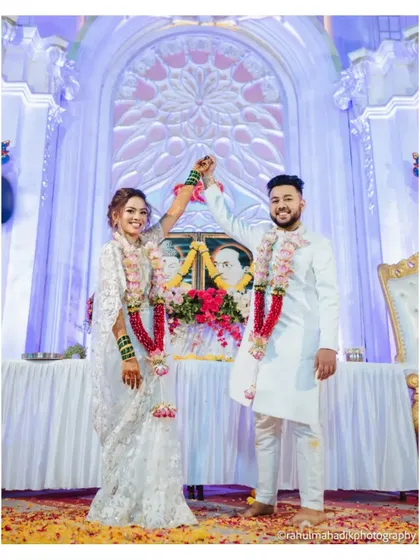 The couple celebrating their union in a Buddhist wedding ceremony, posing in front of a portrait of Dr. B.R. Ambedkar.
