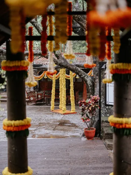 The floral swing viewed through an entrance decorated with marigold torans, creating a beautiful layered perspective of the Haldi event space.