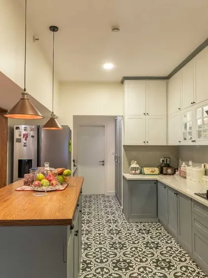A closer look at the island kitchen, showing the patterned floor, matte-finish cabinets, and industrial-style pendant lights.