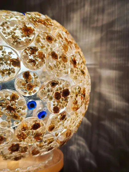 A close-up of the globe lamp, showing how the individual pieces of the varmala are preserved in small circular molds and then assembled to create the sphere. The blue nazar battu adds a pop of color and protection.