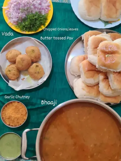 A complete Pav Bhaji platter setup for an event. It includes the rich vegetable bhaji, butter-toasted pav, vada, chutneys, and chopped onions.