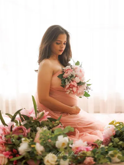 Surrounded by a garden of pink flowers, this mother-to-be holds a matching bouquet in a moment of quiet reflection and connection.