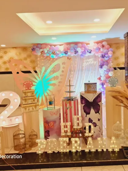 A full stage view of a butterfly-themed second birthday. The large, glowing butterfly wing cutout is the centerpiece of this enchanting decoration.