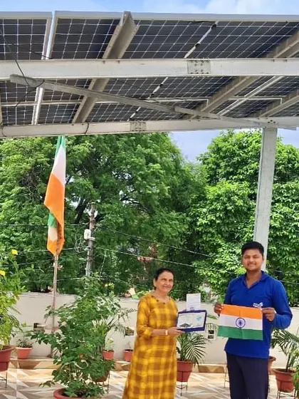 A customer on her beautiful terrace garden, celebrating her switch to solar with our team and the Indian flag.
