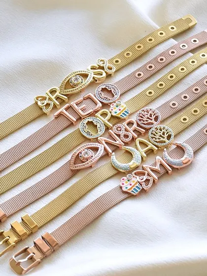 So many stories waiting to be told. Here's a lineup of my custom watchbelt bracelets, available in gold and rose gold, featuring initials and charms like the tree of life and evil eye.
