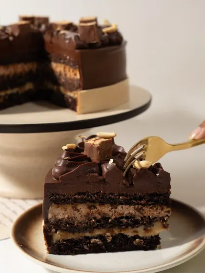 That perfect bite. A fork sinking into a slice of our Snickers Cake, a moment of pure, unadulterated joy.